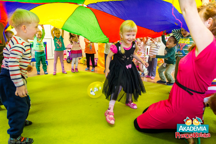 Przedszkolaki bawią się kolorową hustą i balonami.