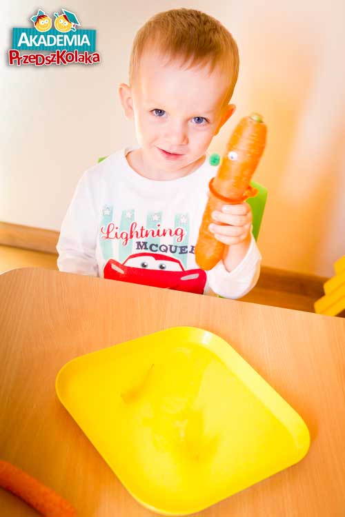 Chłopiec pokazuje ludzika zrobionego z marchewki.