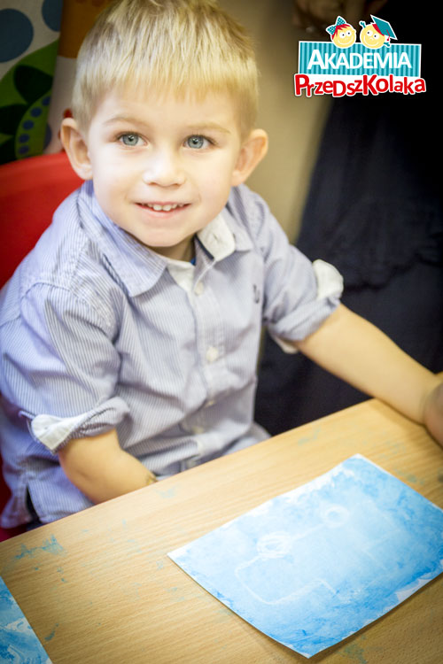 Uśmiechający się Przedszkolak przy ławce. Przed nim „zaczaraowana kartka”