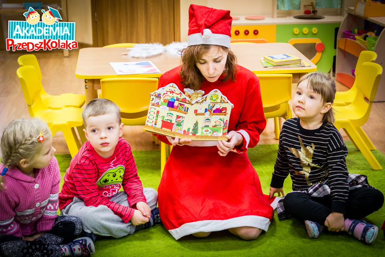 Ciocia w stroju mikołaja czyta świąteczną książeczkę przedszkolakom