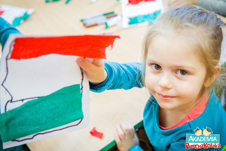 Zajęcia plastyczne. Dziewczynka pokazuje zrobioną flagę Włoch 