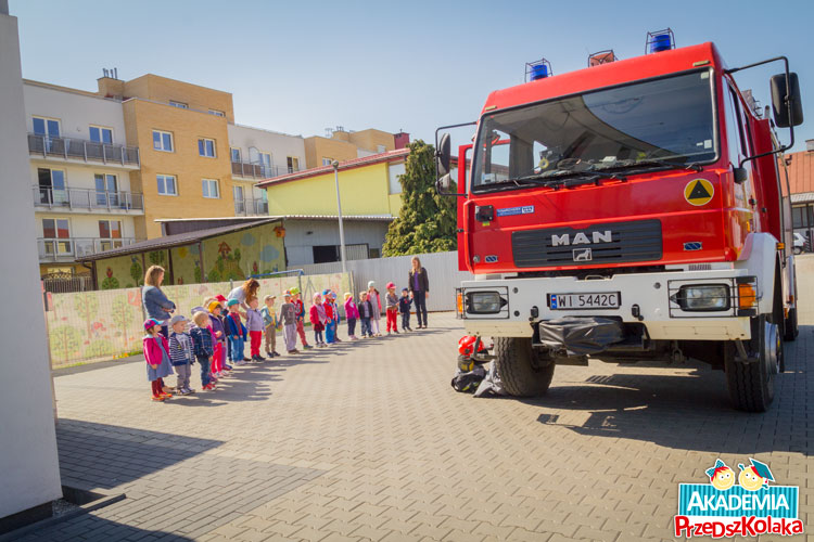 Przedszkolaki stoją na podwórku przed wozem strażackim