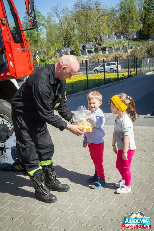 Przedszkolaki dają strażakowi prezent –  domową babkę cytrynową.