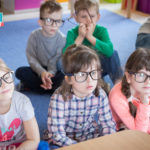 Przedszkolaki siedzą w okularach. W skupieniu słuchają słów cioci.