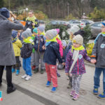 Grupa przedszkolaków stoi na chodniku. Wszyscy mają przypięte naklejki Dzień Ziemi.