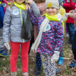 Dumne dzieci pokazują worek z śmieciami które udało im się zebrać w lesie.