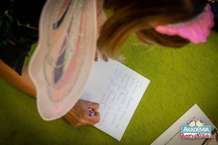 Nauczycielka pisze na kartce A4 początek MądroBajki. Opowieść będzie wspólną pracą nauczycielek, przedszkolaków i rodziców.