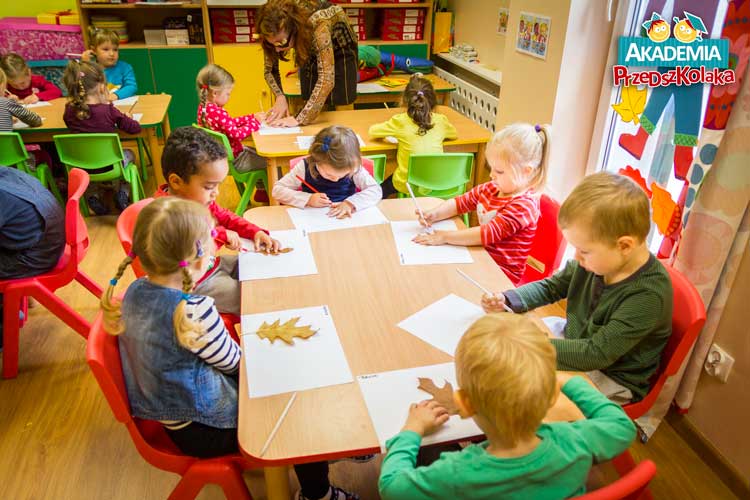 Sala w przedszkolu Akademia Przedszkolaka Białołęka Tarchomin. Dzieci odrysowują liście.
