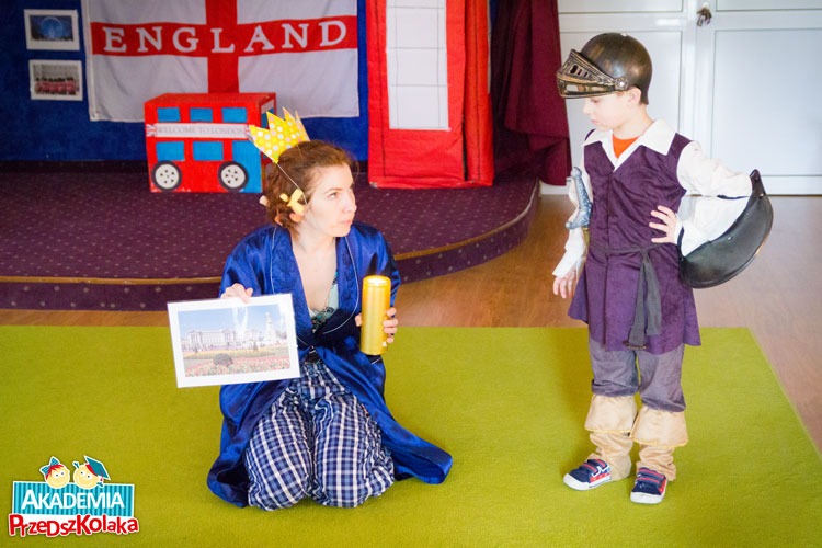 Ciocia przebrana za królową angielską w piżamie. Obok stoi Przedszkolak przebrany za rycerza.