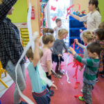 Zajęcia ruchowe. Dzieci tańczą z białymi i czerwonymi wstążkami z bibuły.