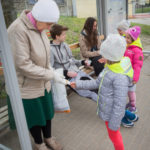 Dzieci na przystanku autobusowym rozdają naklejki informujące o Dniu Ziemi.