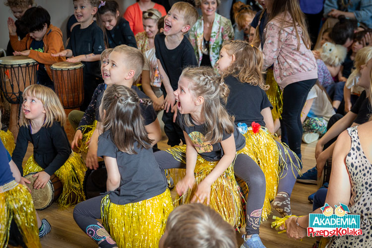 Na zdjęciu jest zbliżenie na kilkoro z dzieci. Mimika buzi wyraźnie pokazuje, że dzieci z całą energią i zaangażowaniem śpiewają piosenkę i grają na instrumentach.